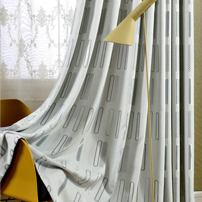 Gråt mørklægningsgardin med grafisk mønster